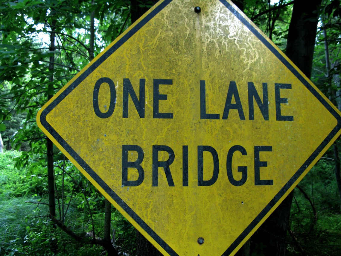 one lane bridge sign in the forest